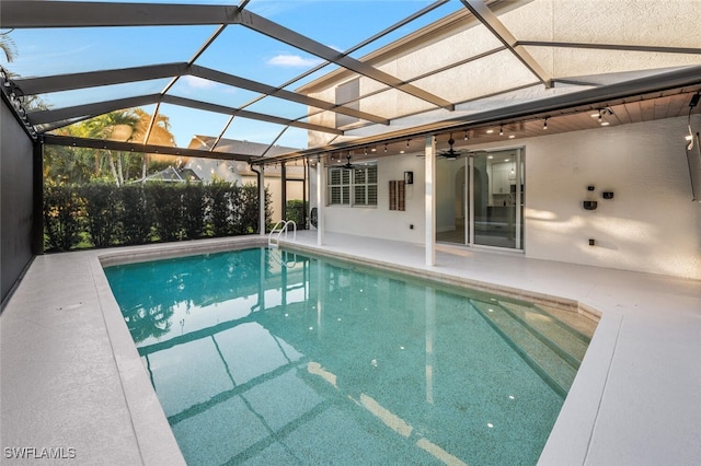 view of swimming pool featuring a patio, glass enclosure, and ceiling fan