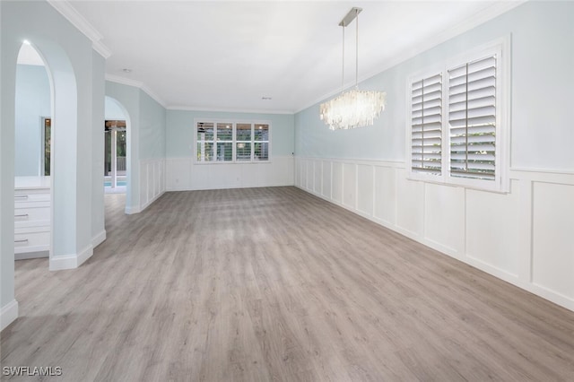 empty room featuring crown molding, a chandelier, and light wood-type flooring