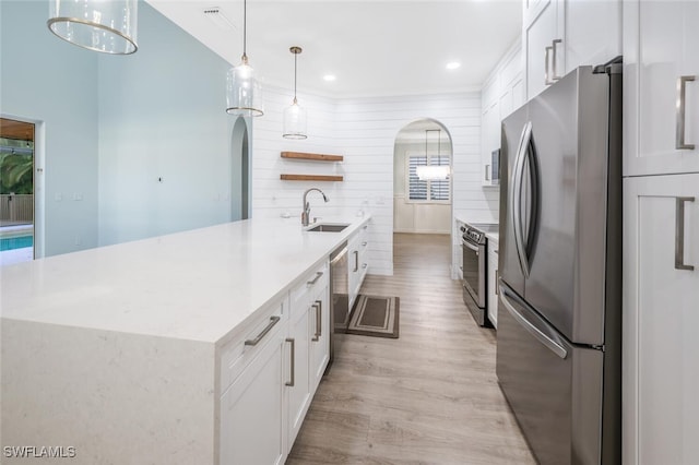 kitchen with white cabinetry, sink, light hardwood / wood-style flooring, pendant lighting, and appliances with stainless steel finishes