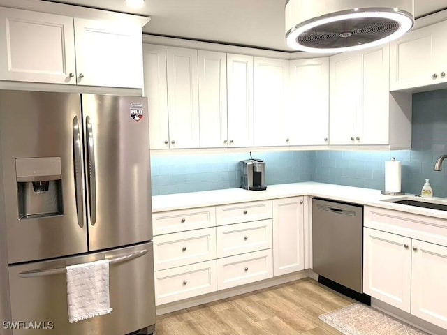 kitchen featuring appliances with stainless steel finishes, light wood-type flooring, white cabinetry, and sink