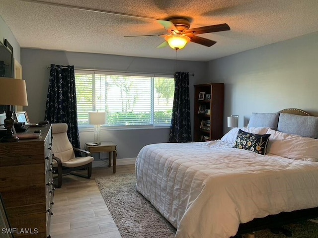 bedroom with ceiling fan, light hardwood / wood-style floors, and a textured ceiling