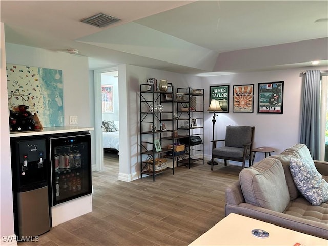 living room featuring bar area, hardwood / wood-style floors, and beverage cooler