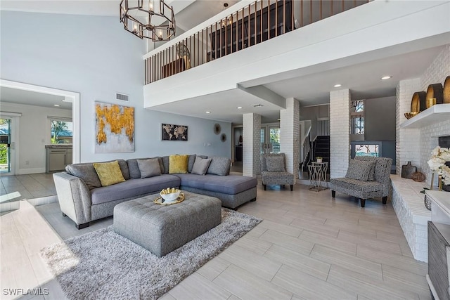 living room featuring a fireplace, a towering ceiling, and a chandelier