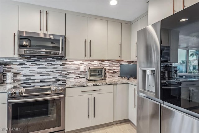 kitchen featuring backsplash, light stone counters, and stainless steel appliances