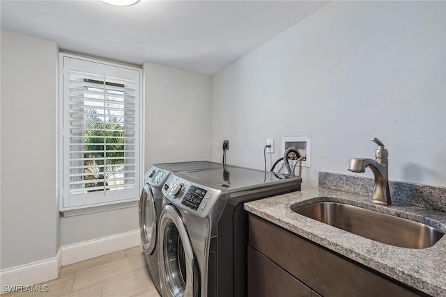 clothes washing area with washer and dryer, sink, and light hardwood / wood-style flooring