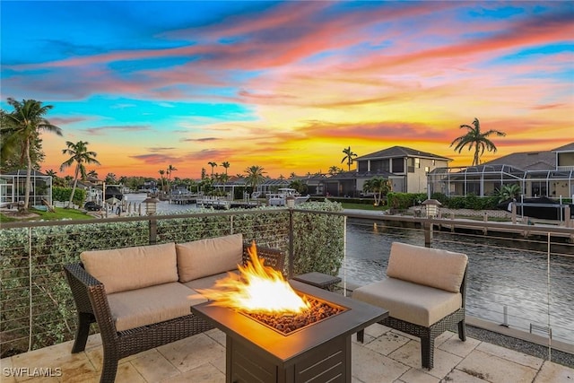 patio terrace at dusk featuring a water view and an outdoor fire pit