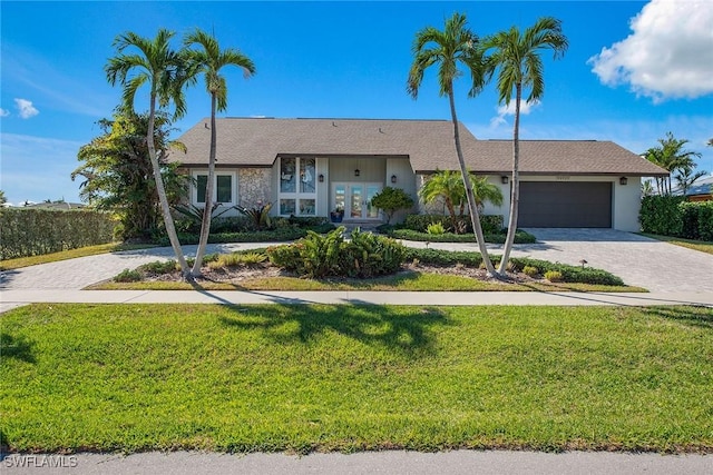 single story home featuring a front lawn, a garage, and french doors