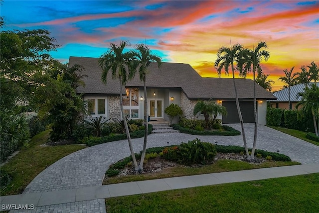 272 N Barfield Dr, Marco Island, FL 34145 - view of front of house featuring curved driveway, a garage, french doors, stone siding, and a front lawn