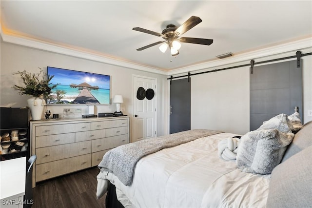 bedroom with ceiling fan, a barn door, and dark hardwood / wood-style flooring