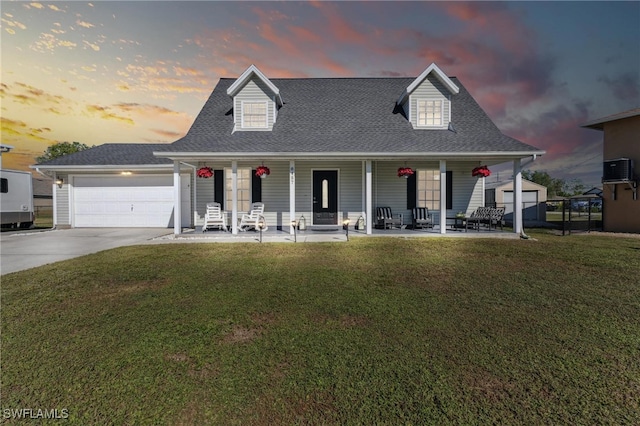 view of front of home with a yard, covered porch, and a garage