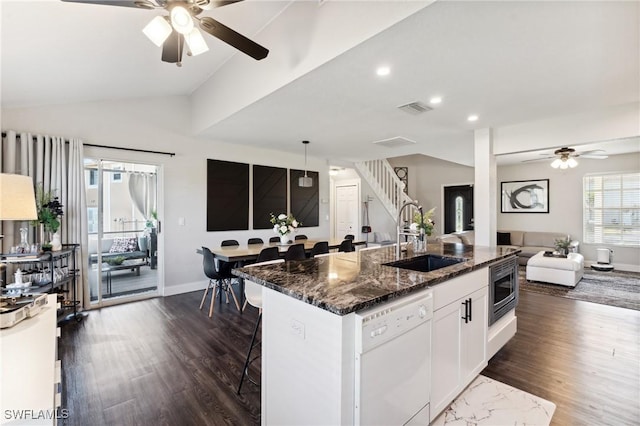 kitchen featuring dishwasher, lofted ceiling, sink, a kitchen bar, and white cabinetry