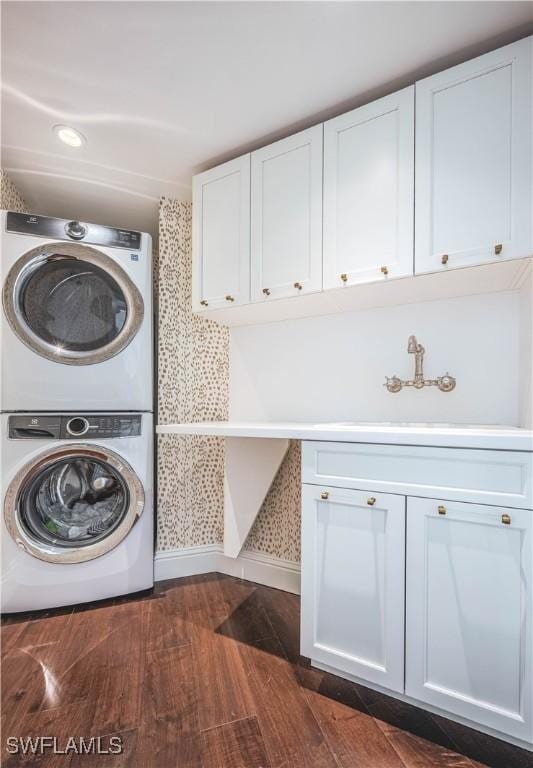 washroom with cabinets, sink, dark hardwood / wood-style floors, and stacked washer / drying machine