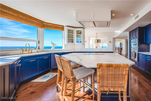 kitchen featuring a wealth of natural light, a center island, a water view, and dark wood-type flooring