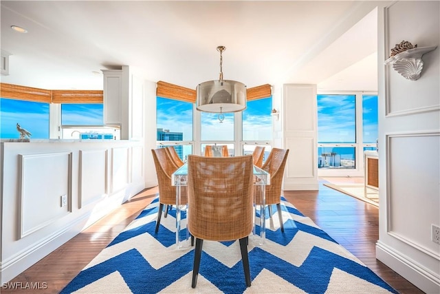 dining space featuring hardwood / wood-style flooring, expansive windows, and a water view