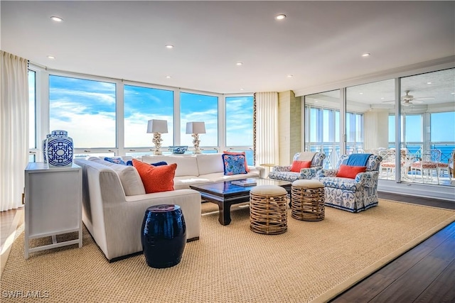 living room with floor to ceiling windows, ceiling fan, a water view, and light hardwood / wood-style floors