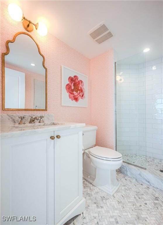 bathroom with vanity, toilet, and tiled shower