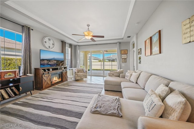 living room featuring a tray ceiling, ceiling fan, and plenty of natural light