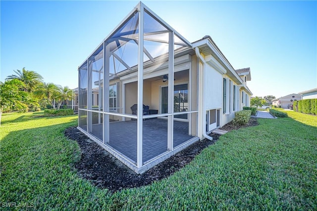 view of property exterior featuring glass enclosure, a patio area, and a lawn