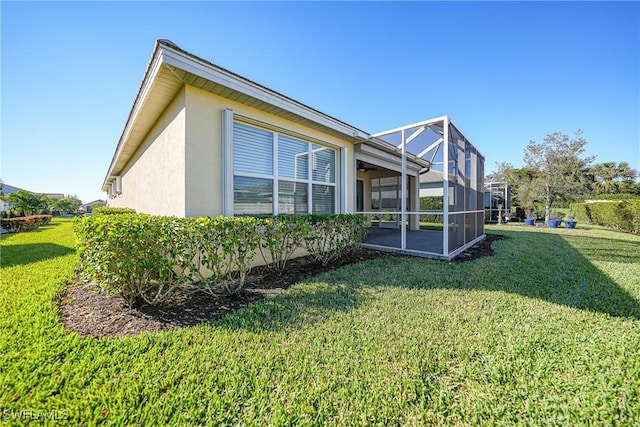 view of side of property featuring a lanai and a lawn