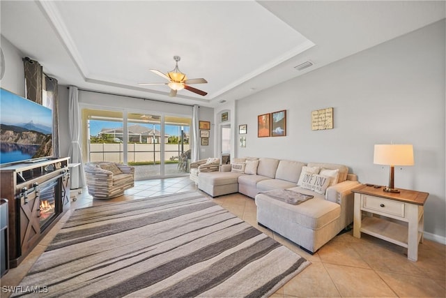 tiled living room featuring ceiling fan and a raised ceiling