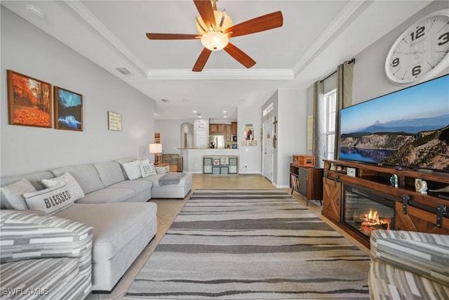 living room with ceiling fan, ornamental molding, and a tray ceiling