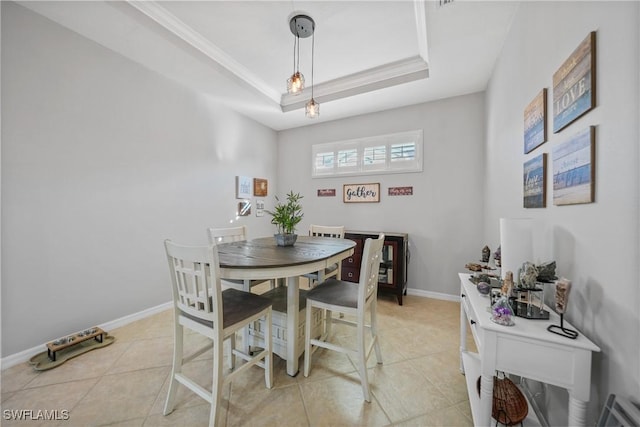 tiled dining area featuring a raised ceiling and ornamental molding