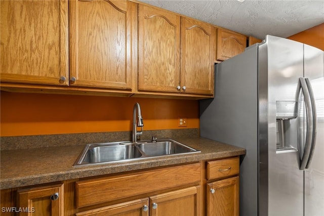 kitchen with a textured ceiling, stainless steel fridge, and sink