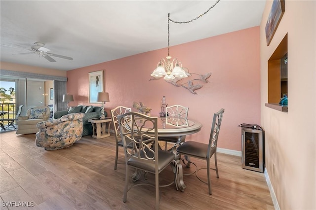 dining space featuring ceiling fan with notable chandelier, light wood-type flooring, and wine cooler