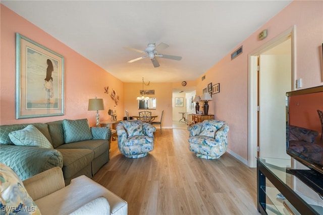 living room featuring light hardwood / wood-style flooring and ceiling fan with notable chandelier