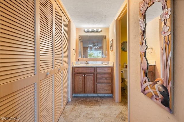 bathroom with a textured ceiling, vanity, and toilet