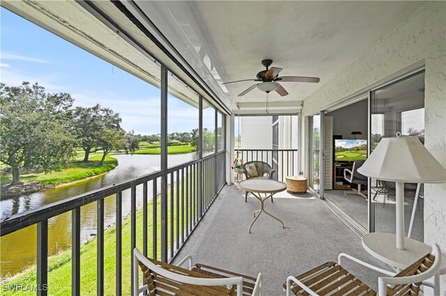 sunroom / solarium featuring a water view and ceiling fan