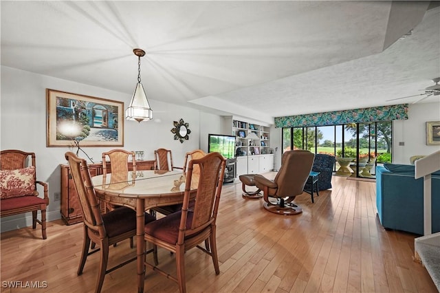 dining space with ceiling fan, light hardwood / wood-style floors, a textured ceiling, and built in shelves