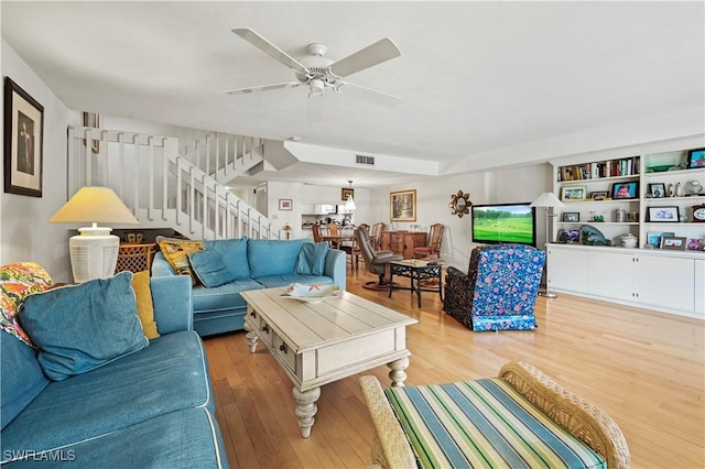 living room featuring ceiling fan, light hardwood / wood-style floors, and built in features