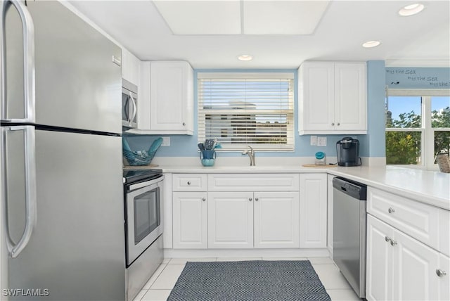 kitchen with light tile patterned floors, stainless steel appliances, white cabinetry, and sink