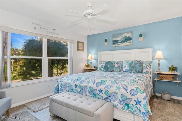 bedroom featuring ceiling fan, light hardwood / wood-style flooring, and multiple windows