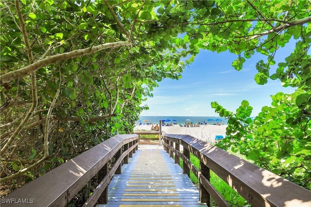 view of dock featuring a water view and a view of the beach