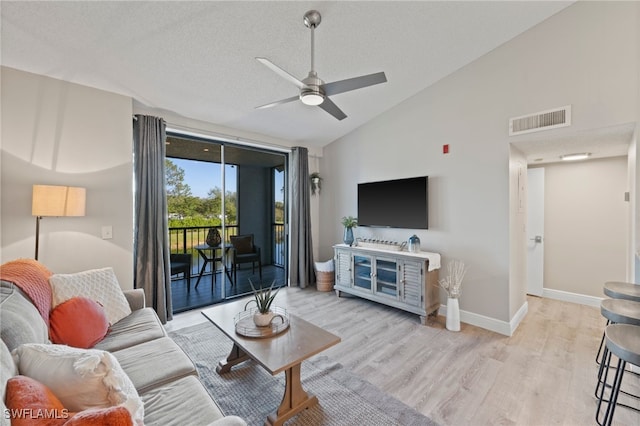 living room featuring ceiling fan, high vaulted ceiling, light hardwood / wood-style floors, and a textured ceiling