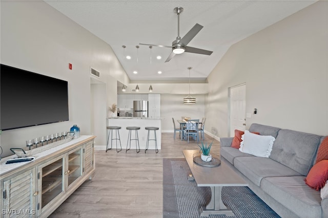 living room with light hardwood / wood-style floors, high vaulted ceiling, and ceiling fan