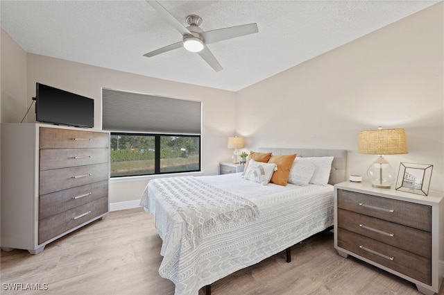 bedroom with ceiling fan, a textured ceiling, and light wood-type flooring