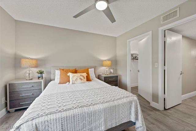 bedroom featuring ceiling fan, a textured ceiling, and light wood-type flooring