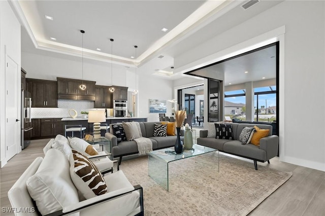 living room featuring a raised ceiling and light hardwood / wood-style floors