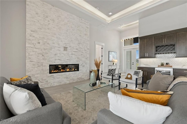 living room featuring a raised ceiling, light wood-type flooring, and a fireplace