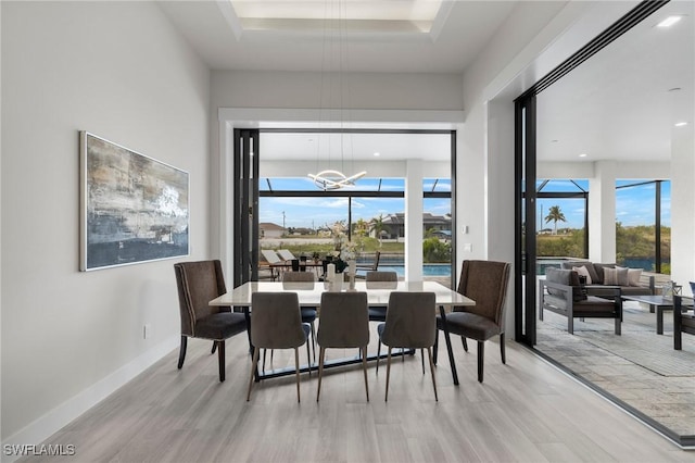 dining space with light hardwood / wood-style floors and a notable chandelier