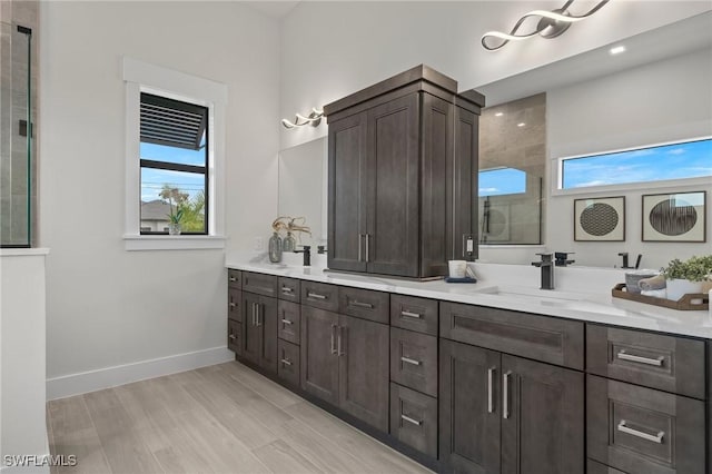 bathroom with plenty of natural light, vanity, wood-type flooring, and tiled shower