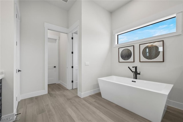 bathroom with a bathing tub, hardwood / wood-style floors, and vanity