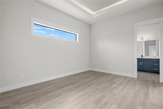 unfurnished bedroom featuring connected bathroom, light hardwood / wood-style floors, and sink