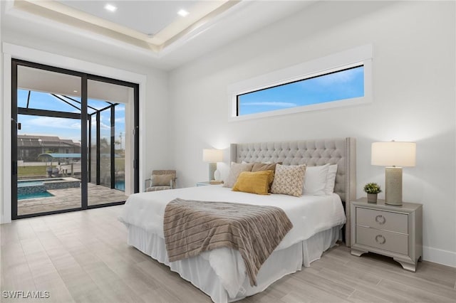 bedroom with a raised ceiling, access to exterior, and light hardwood / wood-style floors