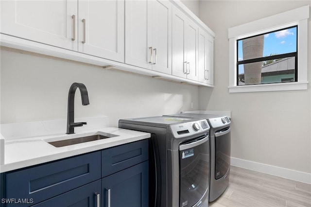 washroom with cabinets, sink, light hardwood / wood-style flooring, and washing machine and clothes dryer