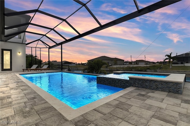 pool at dusk with an in ground hot tub, a patio, and a lanai