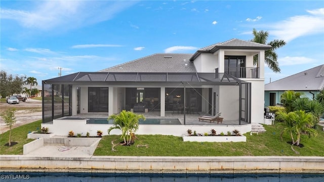 rear view of house with a yard, a balcony, a patio, and a lanai